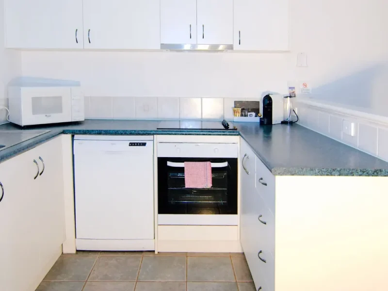 2 Bedroom Kitchen with microwave, coffee machine, oven, dishwasher and window looking out to lush gardens